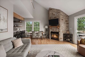 A modern living room with a fireplace, a dining area, and a sofa.