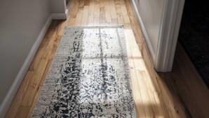 A hallway with wooden flooring and a patterned rug.
