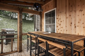 Une terrasse en bois avec un coin bar, un barbecue et un ventilateur.