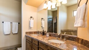 A bathroom with a granite countertop, two sinks, a large mirror, and three wall-mounted lights. - Luxury, 4+ Bedroom, 4 Bath Home on Golf Course with the Best View in Mesquite! (Mesquite)