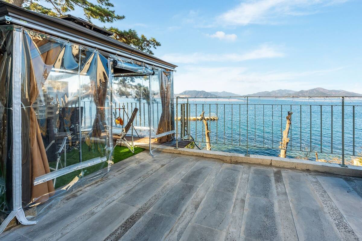 A balcony with a view of the sea, a swing chair, and a stack of bricks.