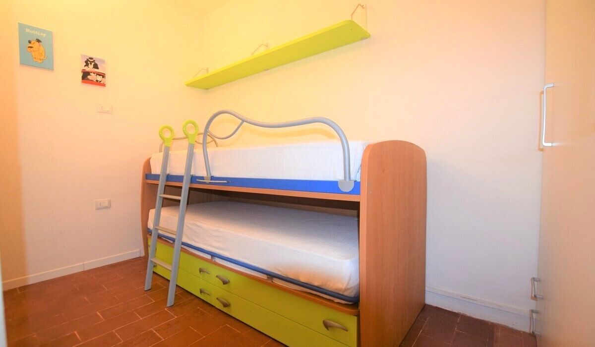 A bunk bed with a green ladder, a white mattress, and a blue headboard.