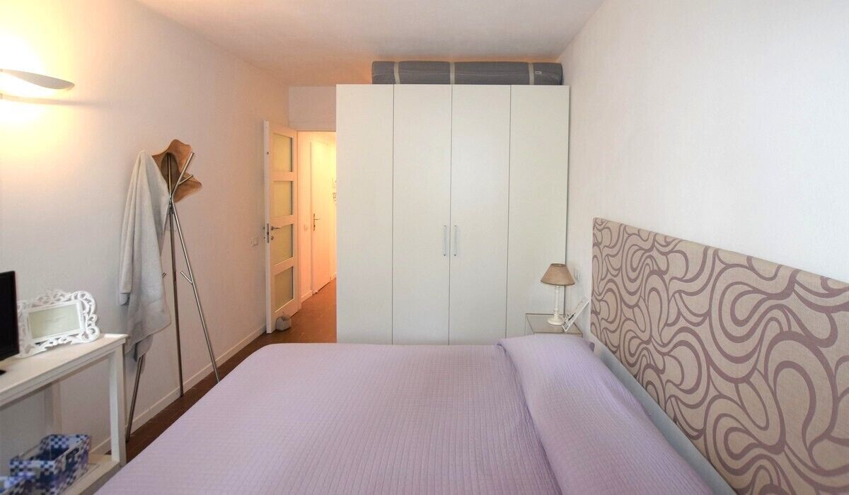 Una camera da letto con un letto, un armadio, un comodino e una lampada.