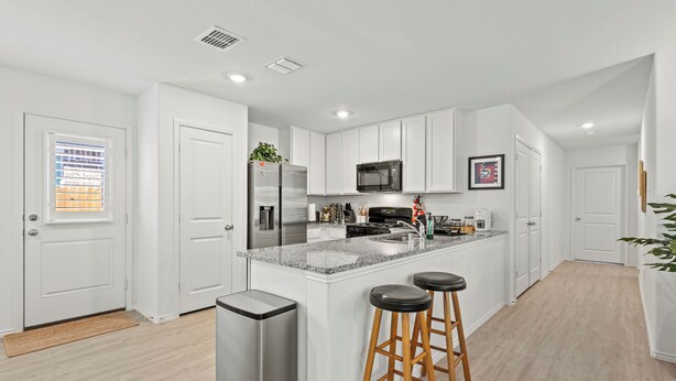 A modern kitchen with white cabinets, stainless steel appliances, and a granite countertop.