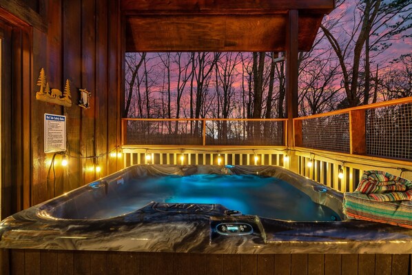 A hot tub with a control panel, surrounded by wooden deck railings, and a sign indicating hot tub safety rules.