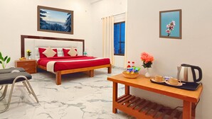 A hotel room with a bed, a chair, a table with a tray, a vase with flowers, and a kettle. - Maa Mandakini Resort By Asapian Hotels (Karwi)