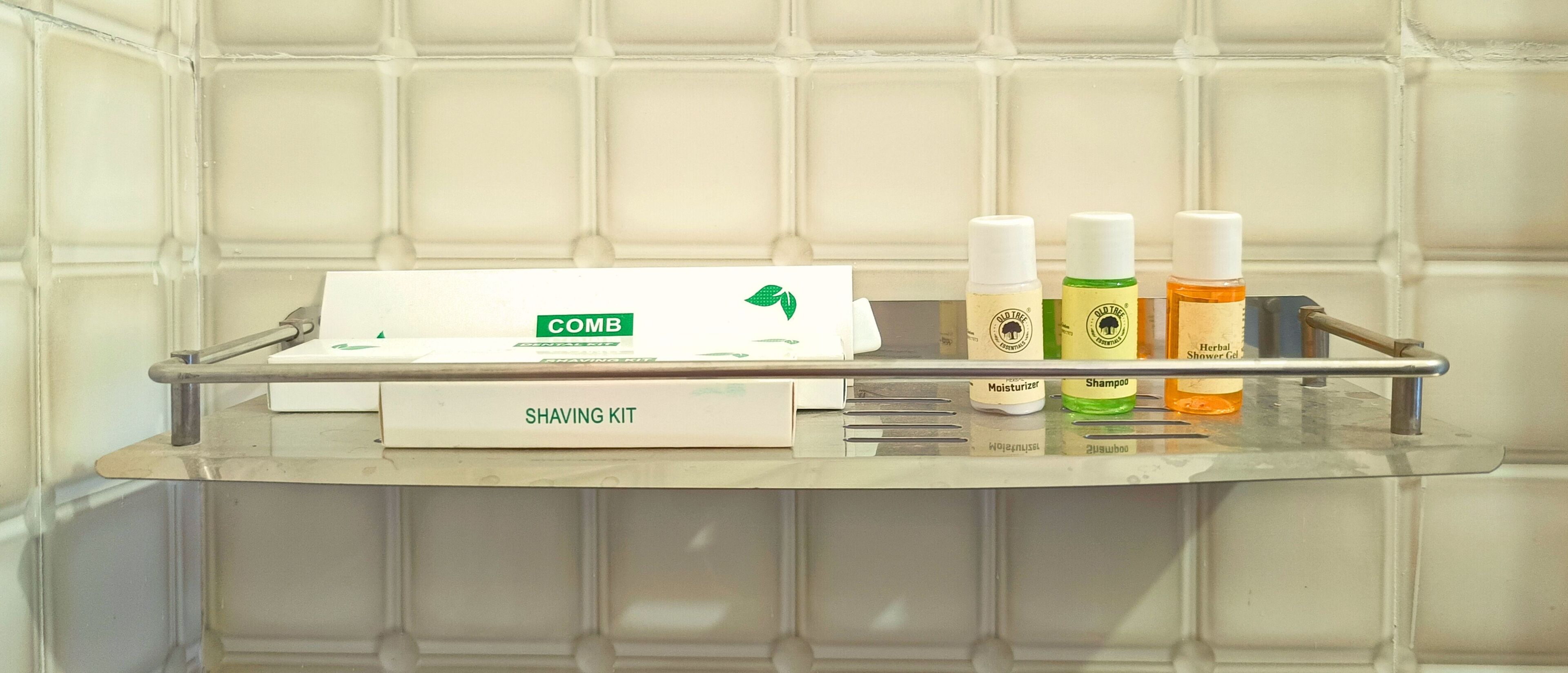 A bathroom with a shaving kit, including a comb, and three bottles of Old Tree products.