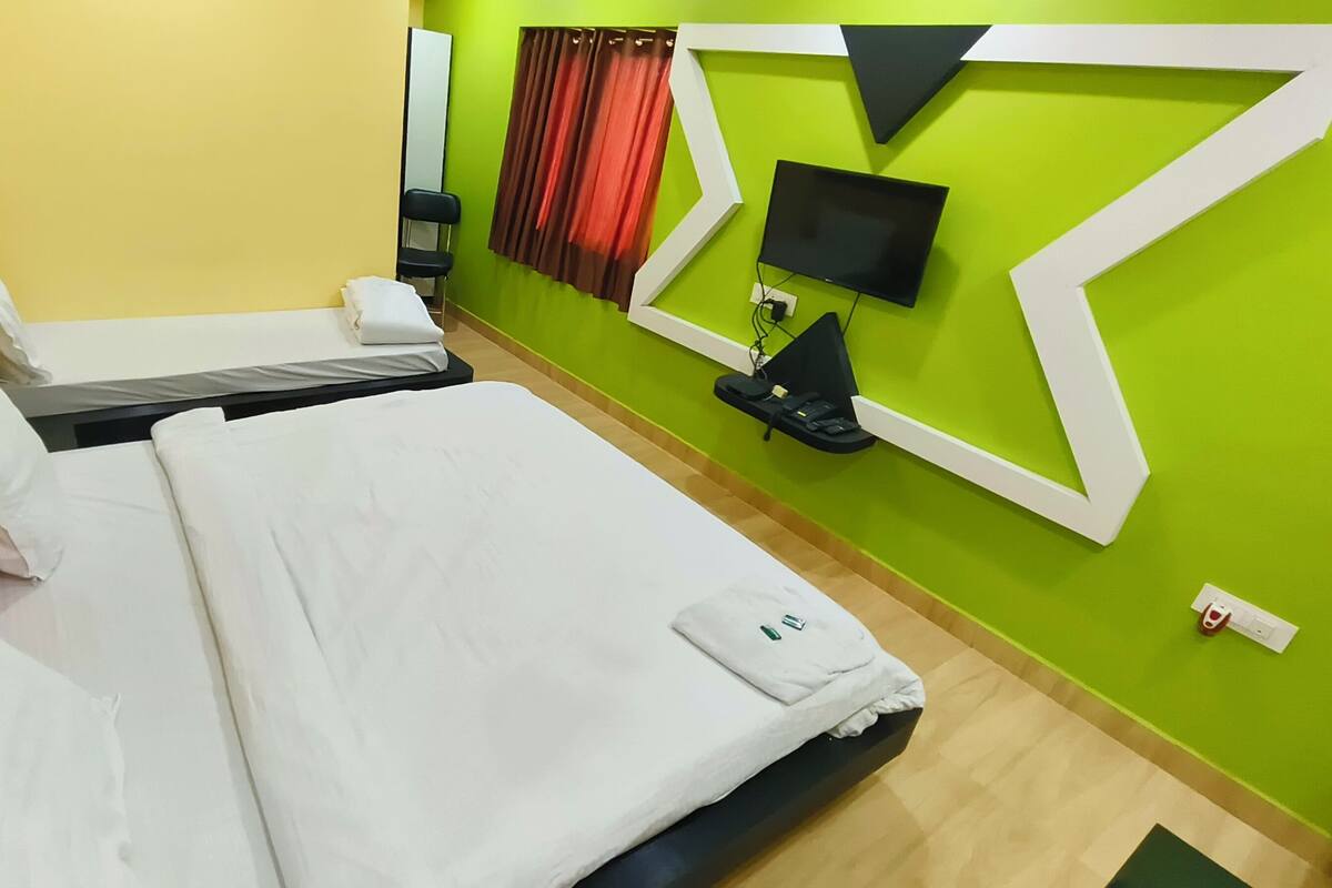 A hotel room with two beds, a flat-screen TV, a desk with a chair, and a mirror.