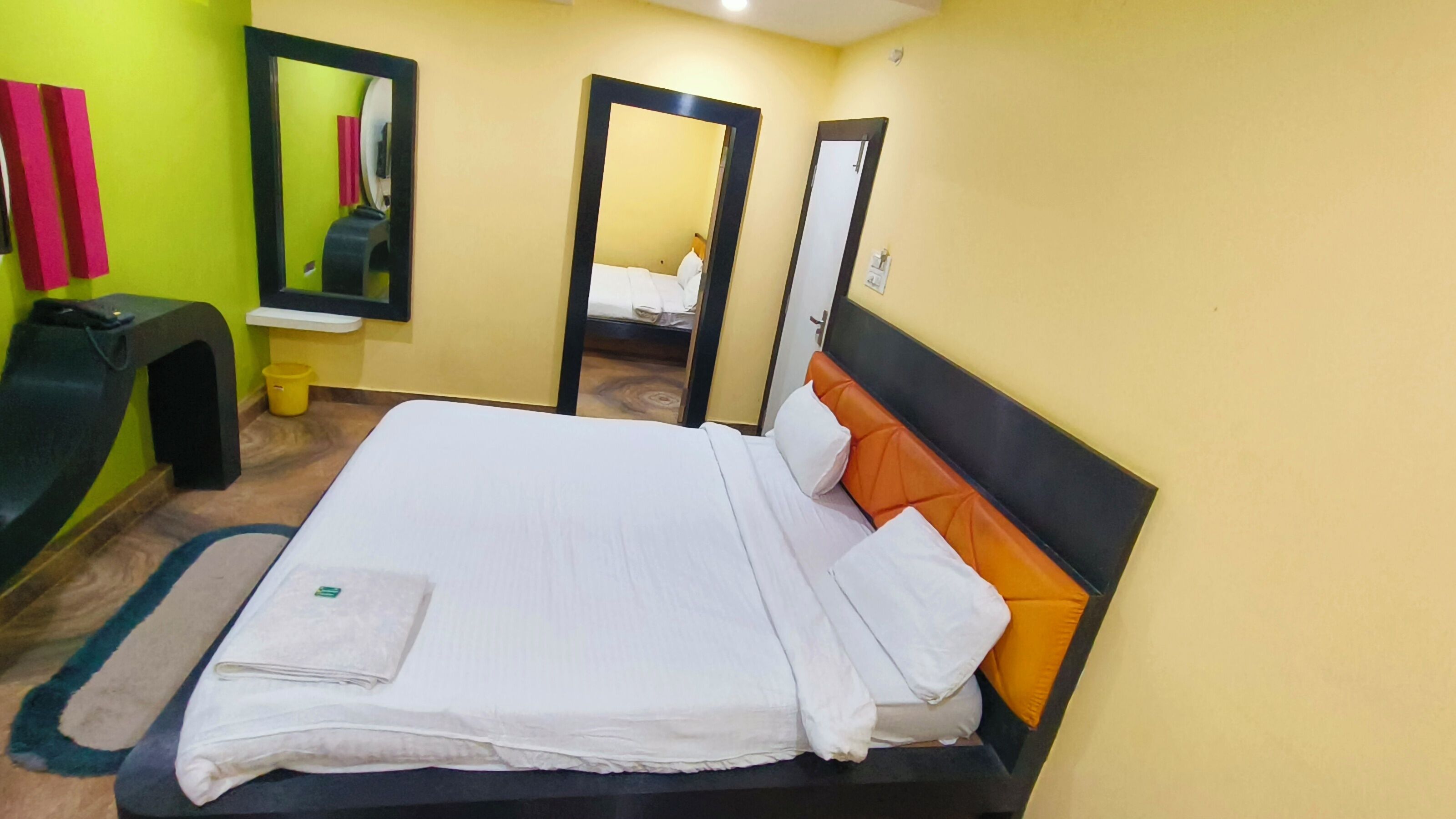 A hotel room with a bed, a desk, a chair, and a mirror.