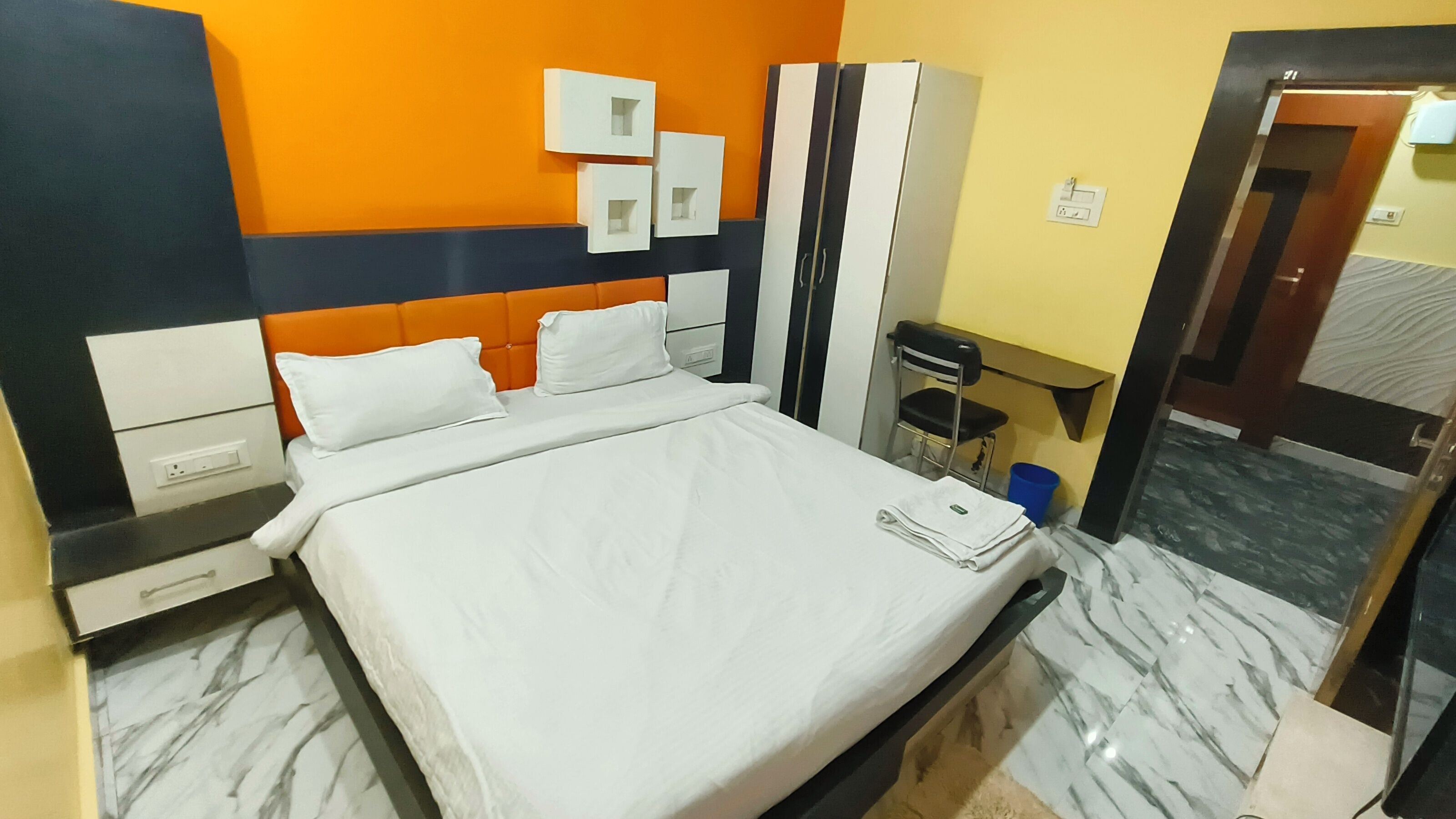 Une chambre d’hôtel comprenant un lit, un bureau, une chaise, une armoire et une porte de salle de bain.
