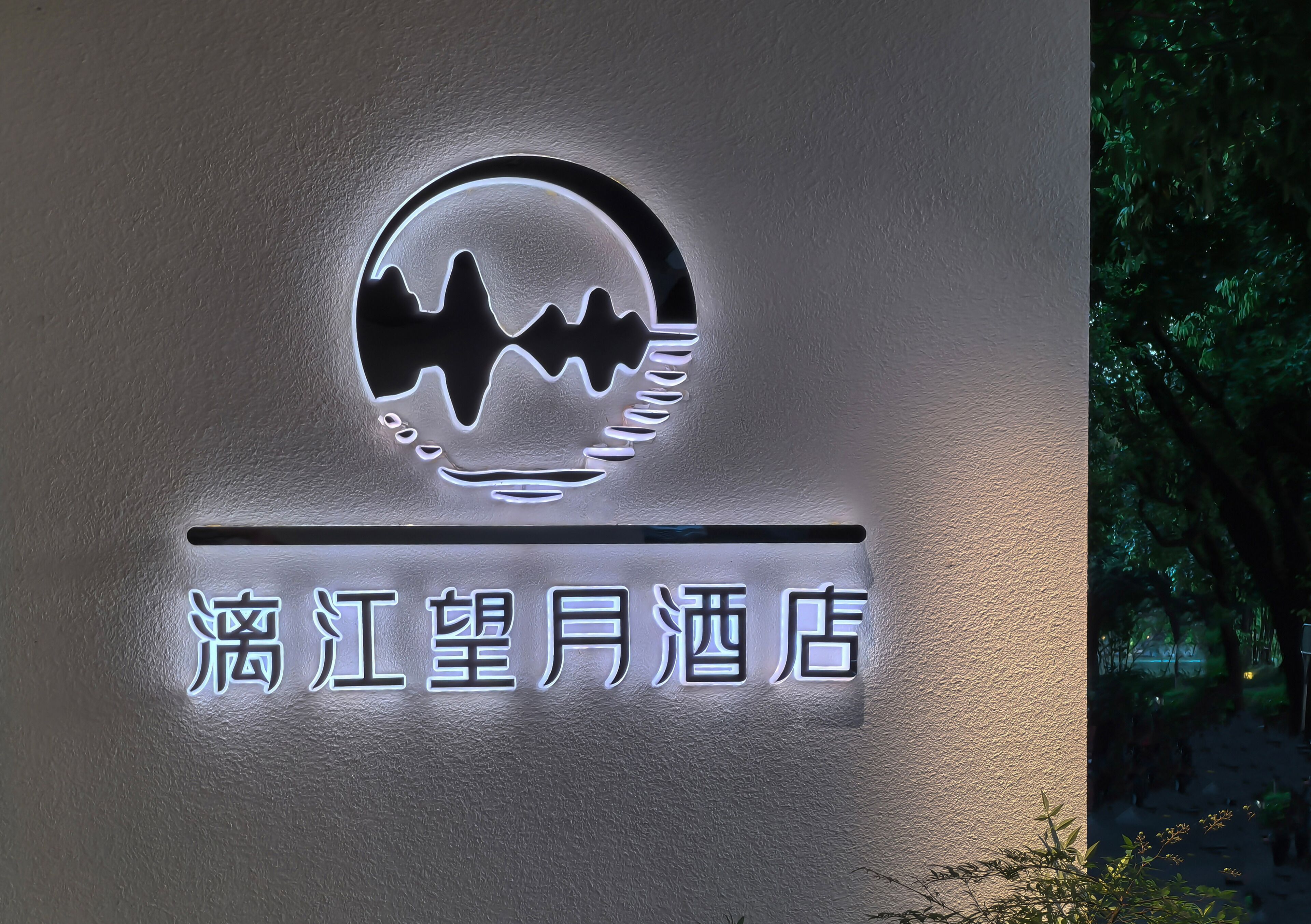 A hotel sign with a logo and name in Chinese characters.
