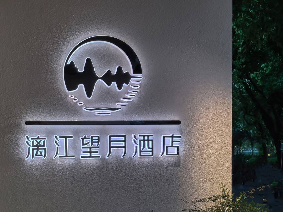 A hotel sign with a logo and name in Chinese characters.