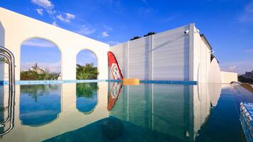 Relax by the pool surrounded by lush palm trees and a modern architectural design.