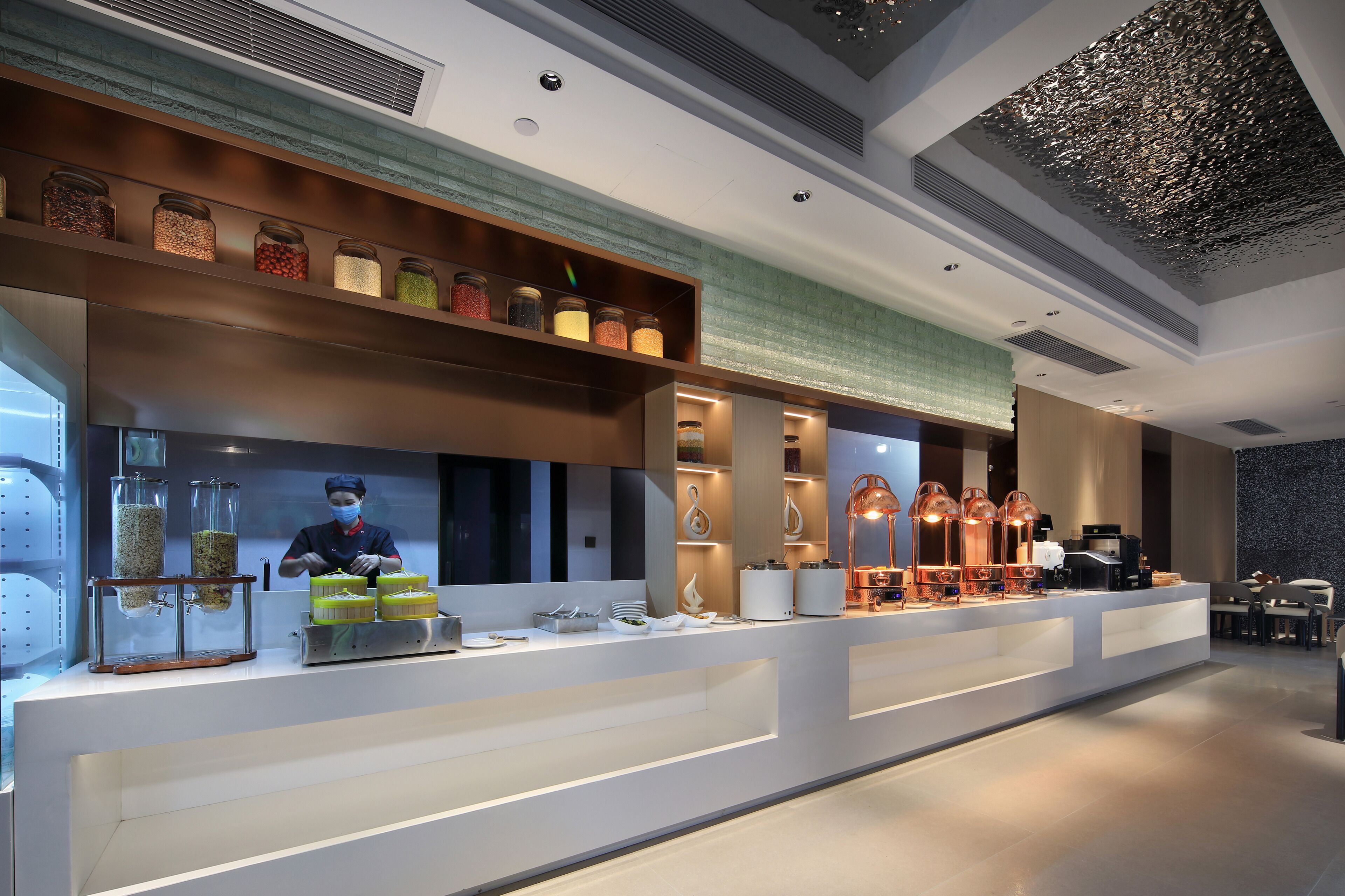 A modern hotel reception area with a long counter, glass display cases, and a variety of amenities including a coffee machine and decorative items.