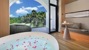 Une salle de bain moderne avec une grande baignoire, un canapé et une table sur laquelle se trouve une théière.