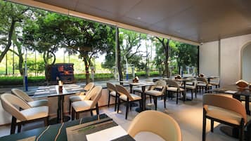 A modern restaurant with indoor seating, large windows, and a view of the outdoors.