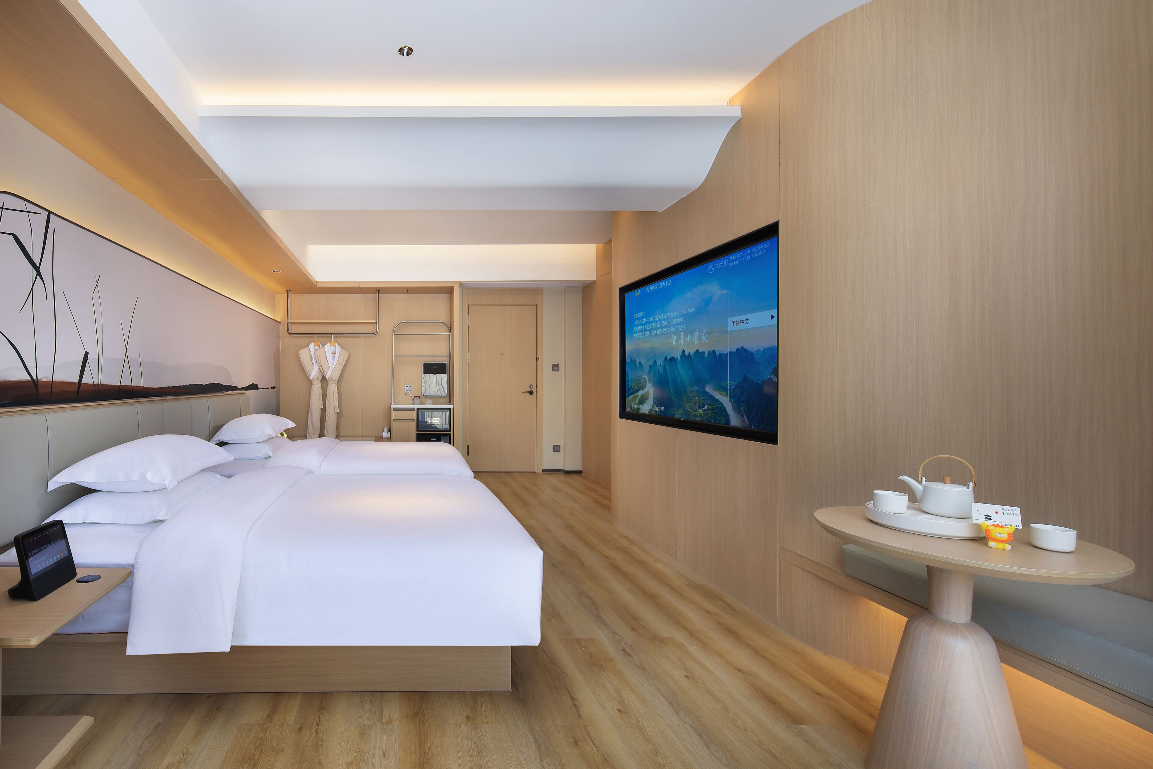 Una habitación de hotel moderna con una cama grande, un televisor de pantalla plana, una mesita con juego de té y un estante fijado a la pared.