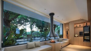 Un salon moderne doté d’une grande fenêtre, d’un canapé, d’une cheminée et d’un meuble de rangement intégré pour les appareils multimédias.