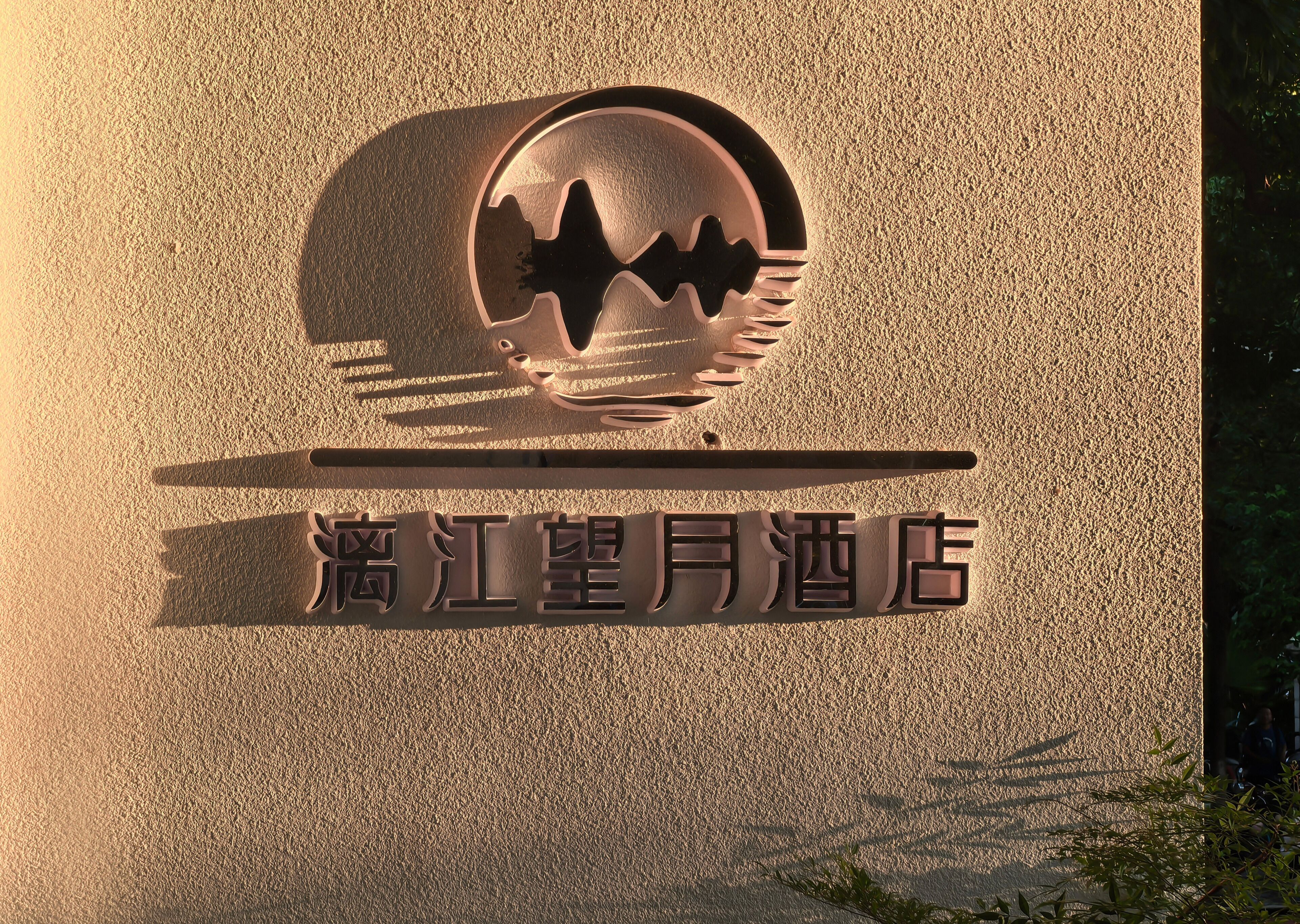 Un letrero de hotel con un logotipo que presenta una montaña y olas estilizadas, y caracteres chinos debajo.