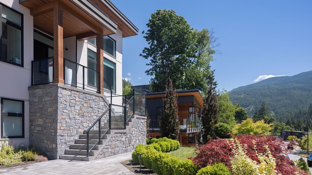 A modern building with a stone facade, wooden accents, and a staircase leading to a balcony.
