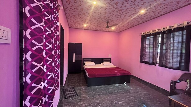 Ein Schlafzimmer mit Bett, Kleiderschrank, Stuhl und einem Fenster mit Vorhängen.
