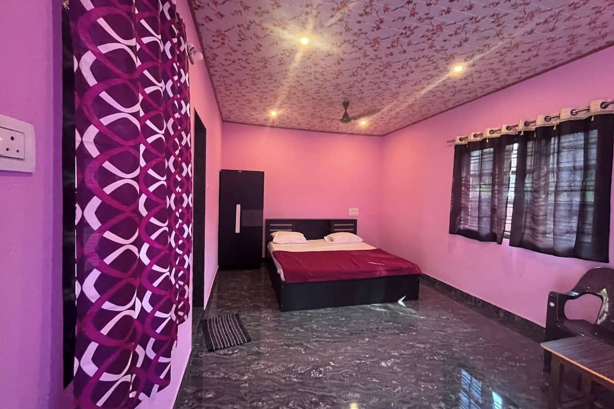 Un dormitorio con cama, armario, silla y ventana con cortinas.