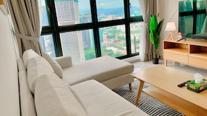 A modern living room with a sofa, a coffee table, and a TV stand. - AGILE Family Apartment By Arman (Kuala Lumpur)