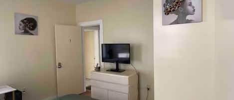 Une chambre à coucher comprenant un lit, une commode, un téléviseur et des œuvres d’art accrochées aux murs.