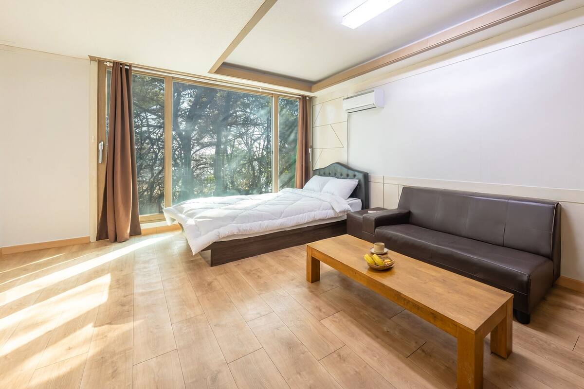 Une chambre à coucher moderne avec un grand lit, un canapé en cuir et une table basse en bois.
