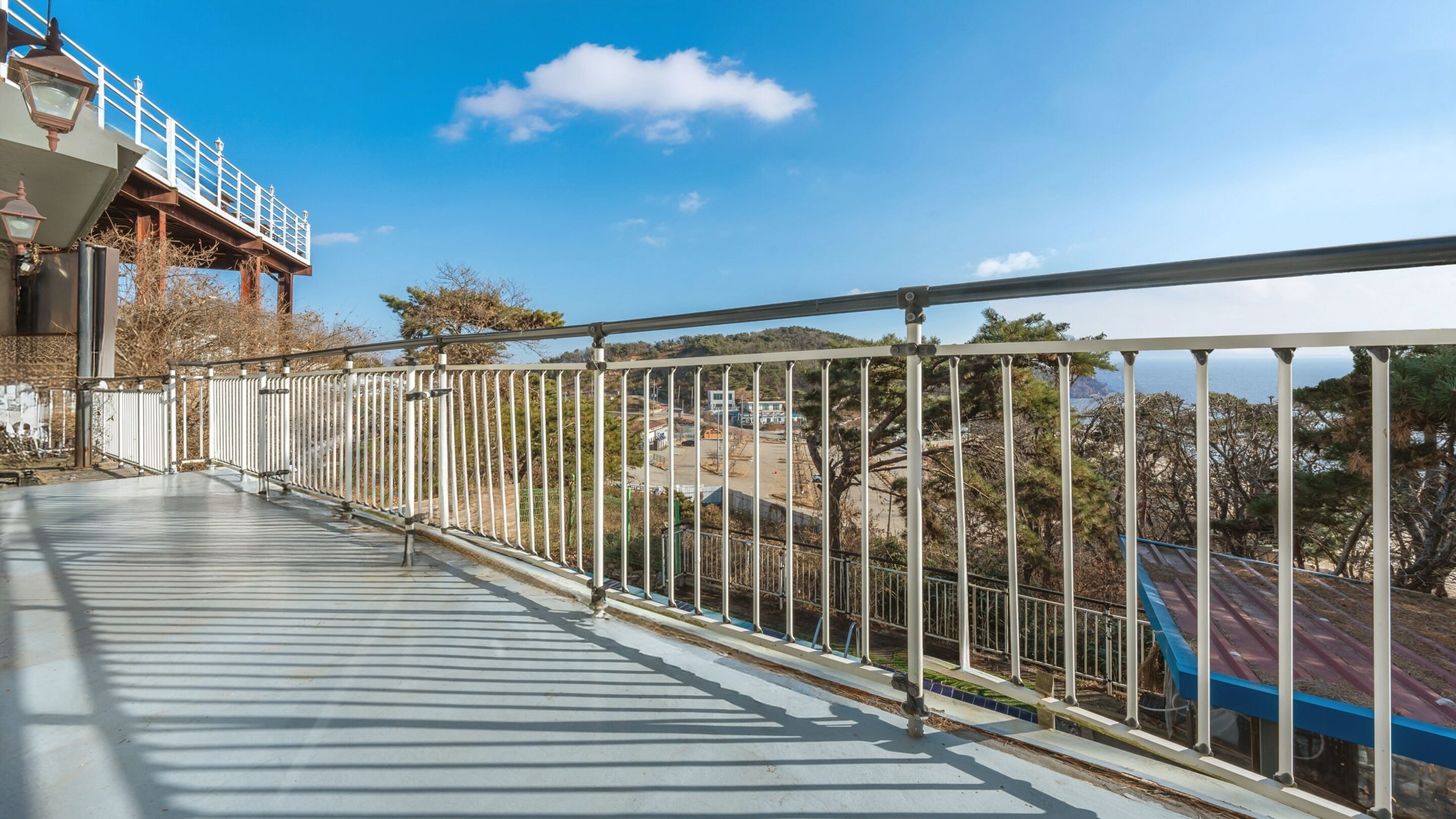 A balcony with a metal railing overlooking a construction site and a view of the sea.