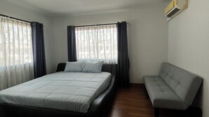Ein Schlafzimmer mit Bett, Sofa, Deckenleuchte und Klimaanlage.