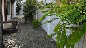 Ein schmaler Innenhof mit einem Kiesweg, umgeben von Gebäuden mit weißen Wänden und dunklen Dächern.