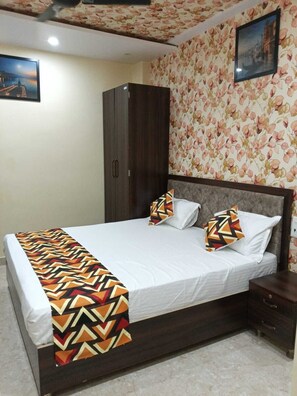 A bedroom with a bed, a wardrobe, a nightstand, and a floral wallpaper.