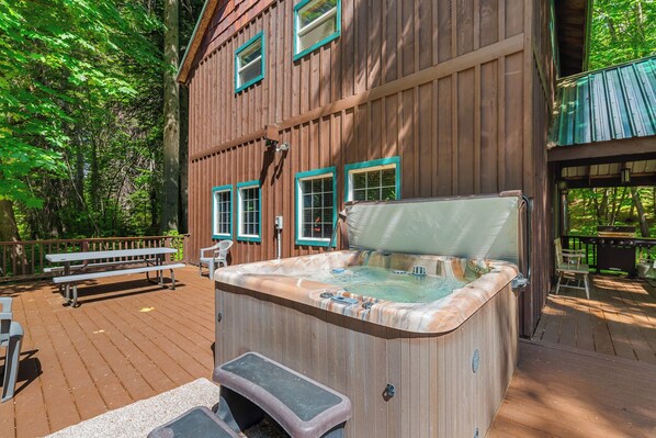 Eine Holzhütte mit Whirlpool, Picknicktisch und Terrasse.