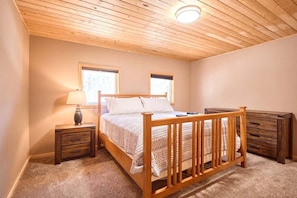 Une chambre à coucher avec un lit en bois, deux tables de chevet, une lampe et une commode.