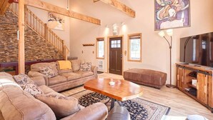A spacious living area with a wooden staircase, a sofa set, a coffee table, and a television. - A cozy cabin near Lake Wenatchee/Leavenworth (Leavenworth)