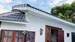 Een traditioneel huis met een pannendak, een houten deur en een raam met gordijnen.