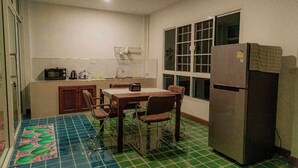 Een kleine keuken met een eettafel, stoelen, een koelkast, een magnetron en een spoelbak.