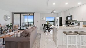 Una cocina moderna con armarios blancos, una isla central y una zona de comedor con vistas.