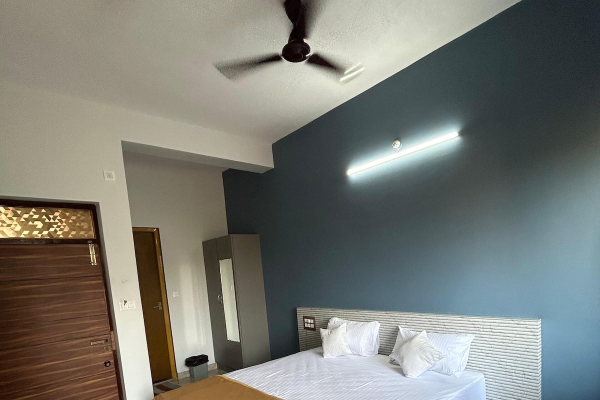 Una camera d'albergo moderna con un letto grande, una ventola a soffitto e un comodino.