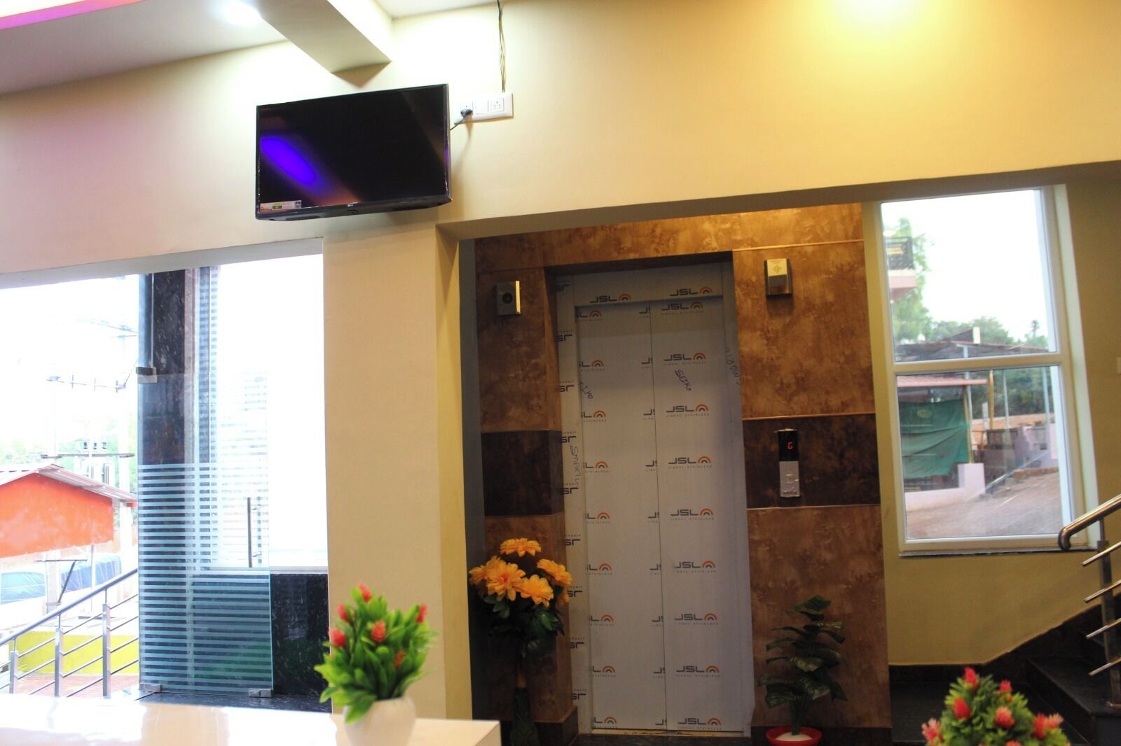 Un área de recepción con mostrador, televisor de pantalla plana montado arriba, una puerta con cerradura de seguridad y ventana con vistas al exterior.