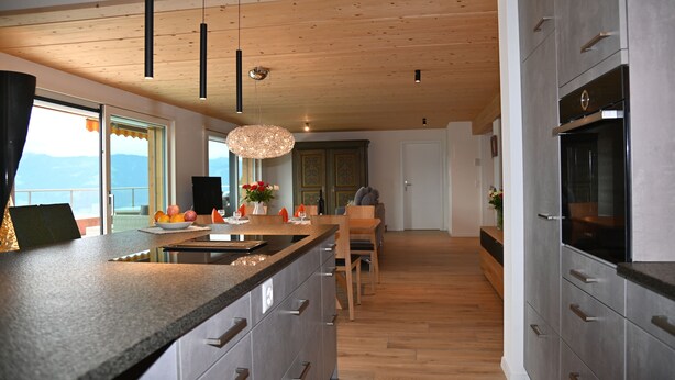Une cuisine moderne avec un plafond en bois, de grandes fenêtres et une vue sur les montagnes.