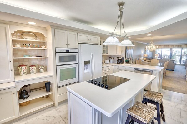 A modern kitchen with white cabinetry, a central island, and a dining area with a chandelier.