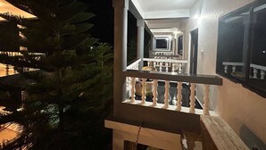 A nighttime view of a balcony with a railing and a view of a pool area. - The Blackbuck Ashwem (Ashvem)