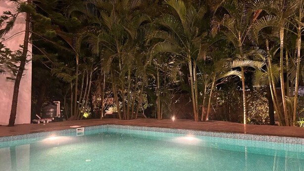 A swimming pool surrounded by palm trees at night. - The Blackbuck Ashwem (Ashvem)