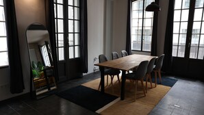 Et moderne spiseområde med et stort bord, stole, store vinduer og en radiator.