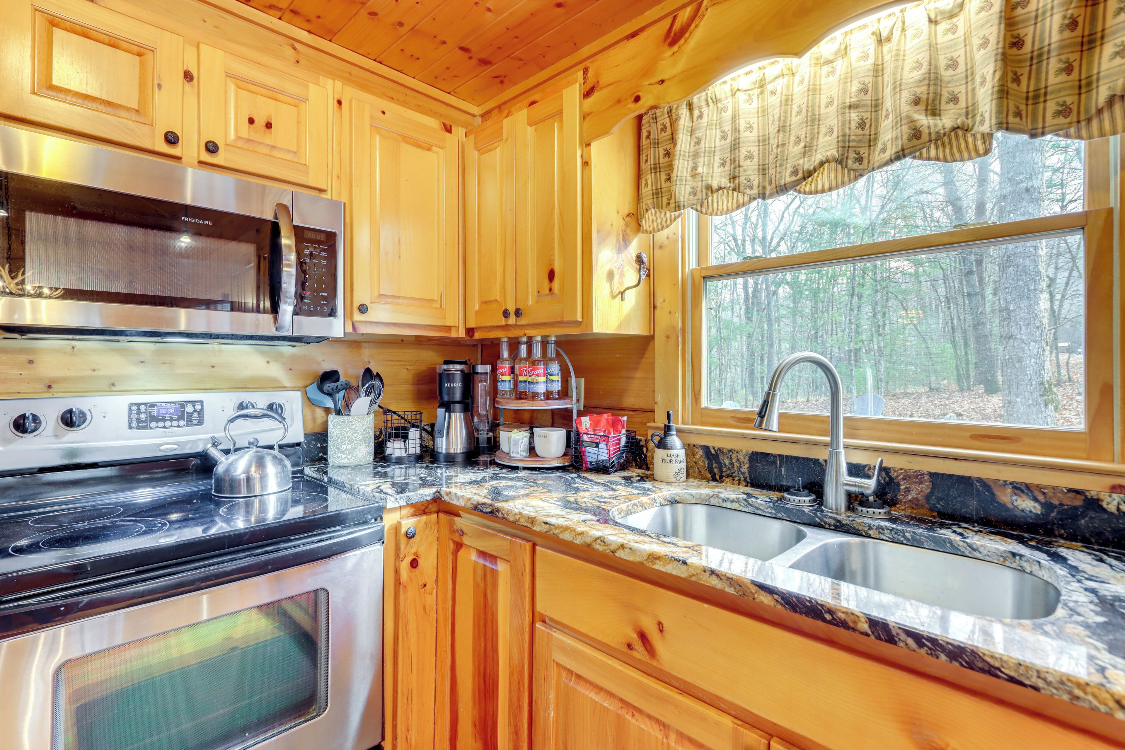 A kitchen with wooden cabinets, a stainless steel stove, a microwave, and a sink.