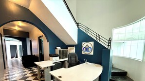 A hotel lobby with a checkered floor, a staircase, a reception desk, and a wall-mounted sign. - ROOMIES HOSTEL Reforma - La Diana (Mexico City)
