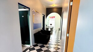 A hallway with a checkered floor, a black sofa, and a map on the wall. - ROOMIES HOSTEL Reforma - La Diana (Mexico City)