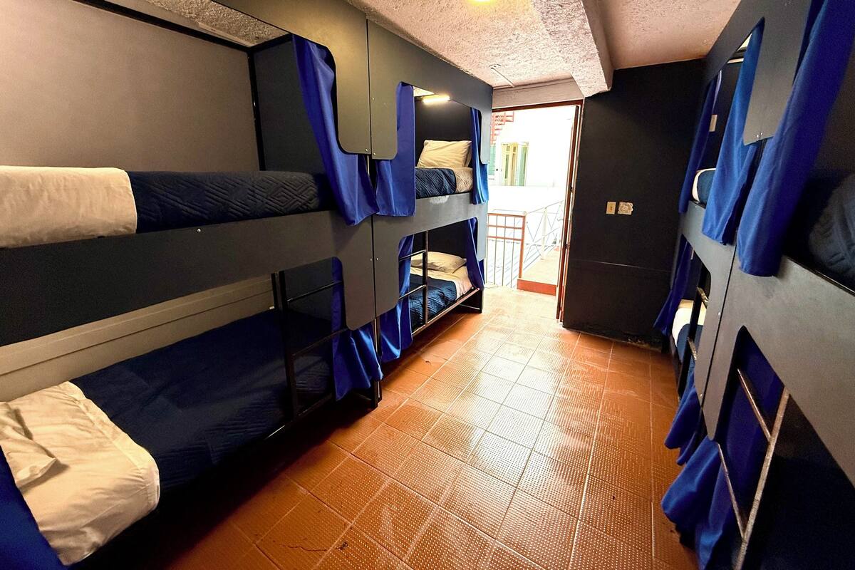 A narrow corridor with bunk beds, a tiled floor, and a door leading to an outdoor area.